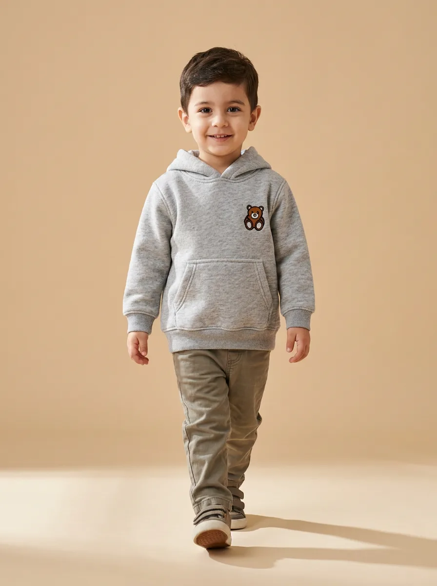 Gri kapüşonlu sweatshirt giymiş, bej stüdyoda yürüyen çocuk: Atalay Studio çıktısı